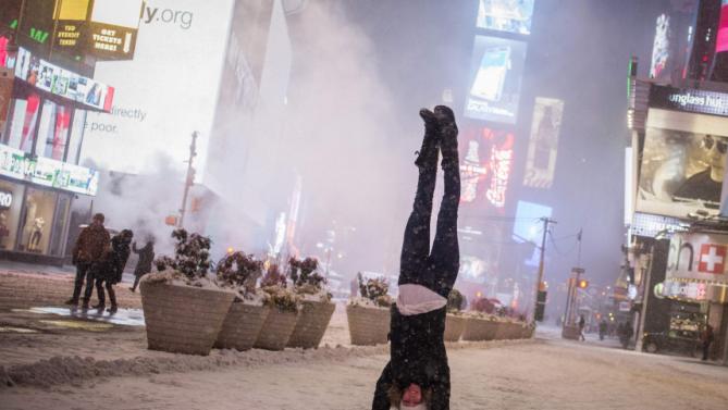 Jamina Goop, from Liechtenstein, does a handstand as she is photographed by a friend during a snow storm in Times Square, New York